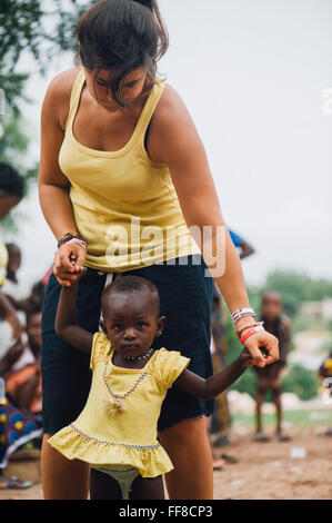 Mali, Afrique - Young caucasian woman bénévoles ayant du plaisir à jouer et danser avec un bébé femelle noire près de Bamako Banque D'Images