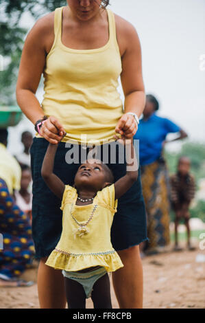 Mali, Afrique - Young caucasian woman bénévoles ayant du plaisir à jouer et danser avec un bébé femelle noire près de Bamako Banque D'Images