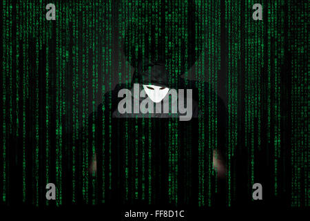 Un homme masqué à un ordinateur portable symbolisant les dangers de l'Internet. Banque D'Images