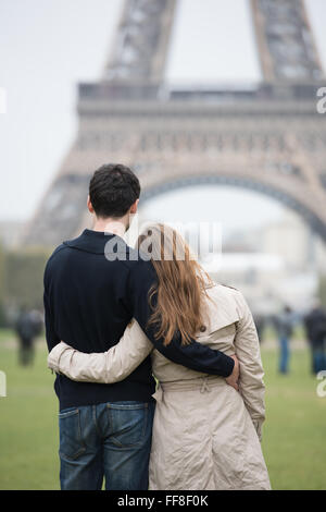 Jeune couple, man and woman standing in front of Tour Eiffel, Paris, France, hugging Banque D'Images