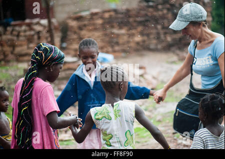 Mali, Afrique - Young caucasian woman having fun dans un anneau autour du Rosey avec les enfants d'Afrique noire près de Bamako Banque D'Images