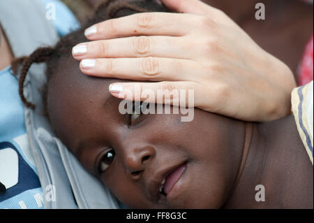 Mali, Afrique - Caucasian woman mains caressant jeune fille noire Banque D'Images