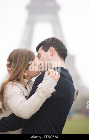 Jeune couple, man and woman standing in front of Tour Eiffel, Paris, France, en l'embrassant Banque D'Images