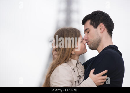 Jeune couple, man and woman standing in front of Tour Eiffel, Paris, France, à la recherche dans chaque autres des yeux, presque s'embrasser Banque D'Images