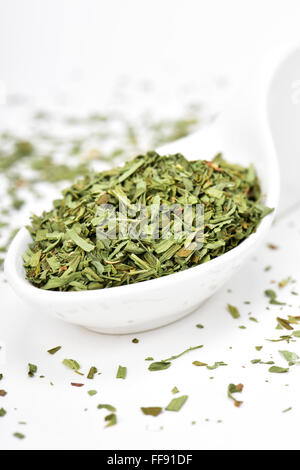 Une pile de feuilles d'estragon haché dans un bol en céramique sur une surface blanche Banque D'Images