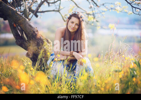 Smiling gypsy woman posing parmi les fleurs . La paix et l'harmonie Banque D'Images