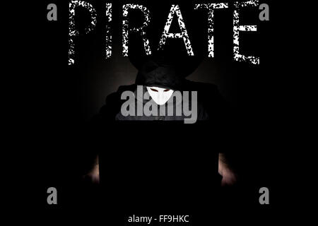 Un homme masqué à un ordinateur portable symbolisant les dangers de l'Internet. Banque D'Images