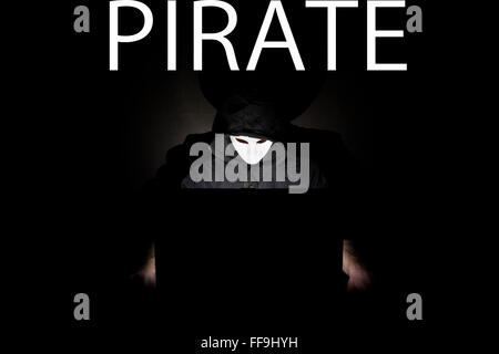 Un homme masqué à un ordinateur portable symbolisant les dangers de l'Internet. Banque D'Images