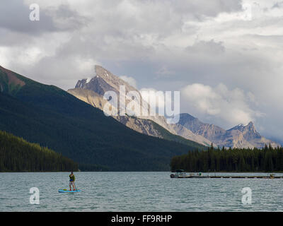 Un stand-up paddleboarder fait son chemin à travers le lac Maligne sur l'image. Le Parc National de Jasper, Jasper, Alberta, Canada. Banque D'Images