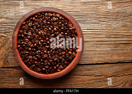 Grains de café dans un plat d'argile avec une belle texture sur fond de table en bois vieilli Banque D'Images