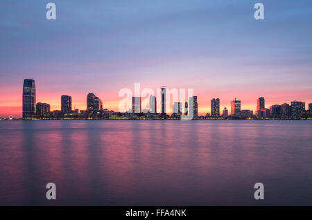 Un magnifique coucher de soleil sur les gratte-ciel de Jersey City et de la rivière Hudson, avec le ciel rose reflète dans l'eau. Banque D'Images