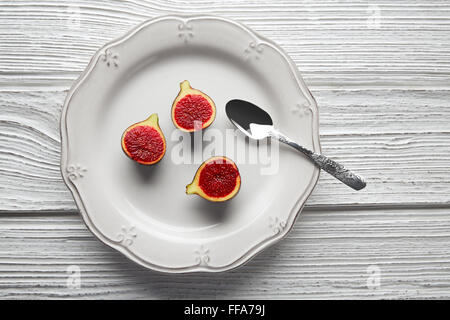 Figues matières cutted fig fruits sur plaque blanche et table en bois Banque D'Images