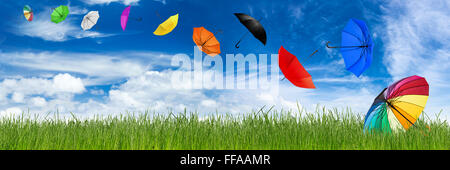 Parasols colorés s'envoler en face de ciel bleu et vert gazon naturel Banque D'Images