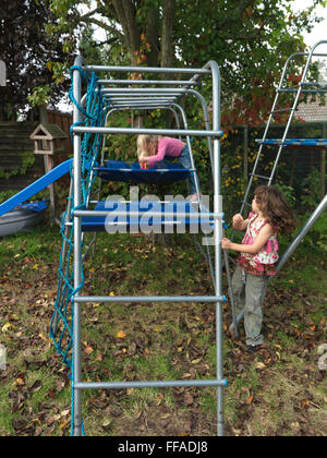 Deux Soeurs Filles sur Escalade en Angleterre le jardin Banque D'Images