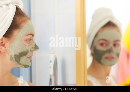 Soins de la peau. Femme dans la salle de bains avec l'argile verte masque de boue sur le visage. Fille prendre soin de peau huileuse. Soin de beauté. Banque D'Images