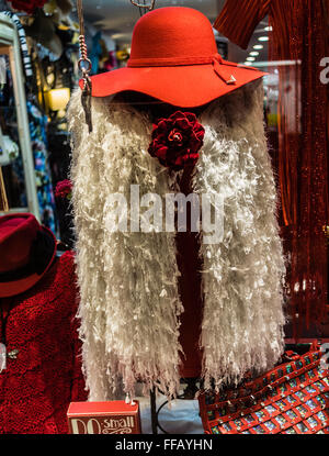 Red Hat et la femme blanche à froufrous gilet inhabituelle, qui pourrait être porté comme un foulard affiché dans une fenêtre de magasin de vêtements Banque D'Images