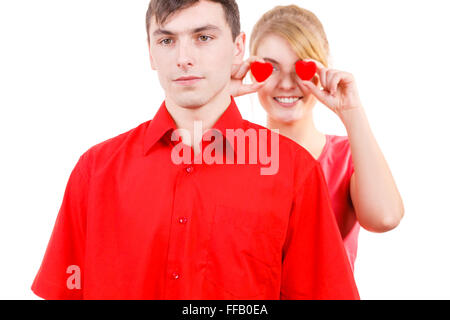 Couple. Petit ami sérieux et sa petite amie follement amusante holding coeurs rouges au-dessus des yeux. Valentines Day ou amour non partagé. Banque D'Images