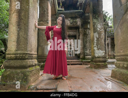 Jeune fille dans une robe rouge, porte de l'Est, Ta Prohm Temple, Angkor Thom, Siem Reap, Cambodge Banque D'Images
