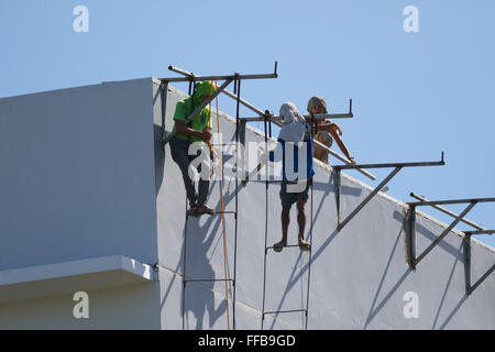 Une scène commune dans l'industrie de la construction des Philippines - les travailleurs du bâtiment de façon précaire accrocher des échelles de fortune métallique soudé. Banque D'Images