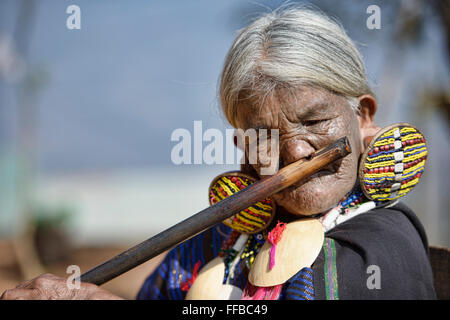 Shen, un lacet Magan Chin femme avec tatouages visage joue, flûte traditionnelle, l'État Chin, le Myanmar. Banque D'Images