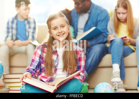 Petite écolière avec open book looking at camera avec Smile Banque D'Images