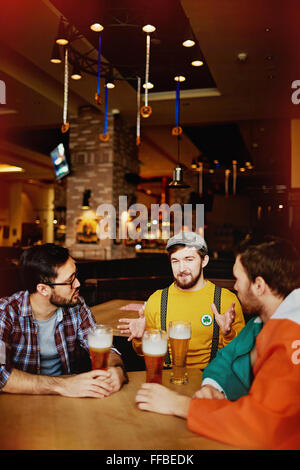 Groupe d'hommes parlant multi-ethnique tout en restant assis dans un pub Banque D'Images