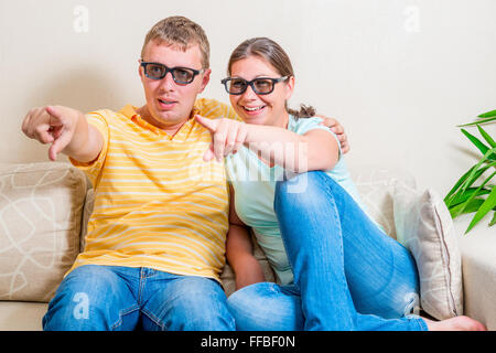 Cheerful couple regardant un film drôle à la maison en 3D sans lunettes Banque D'Images