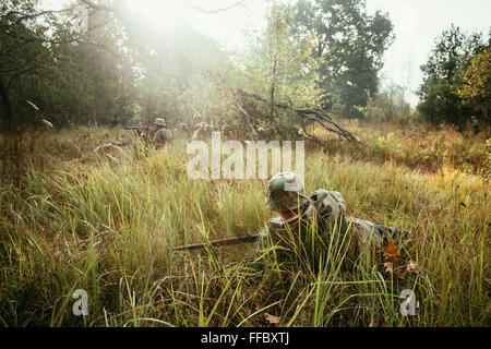 Non cachés de la reconstitution médiévale habillé comme la Seconde Guerre mondiale, soldat de la Wehrmacht allemande assis avec fusil dans une embuscade dans la forêt brumeuse. Banque D'Images