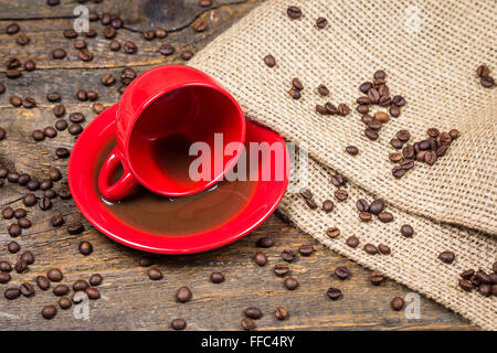 Tasse de café rouge avec renversé du café et les grains de café Banque D'Images