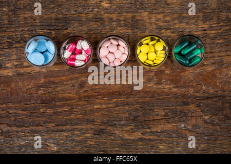 Divers comprimés et gélules dans des contenants en verre sur la table en bois Banque D'Images