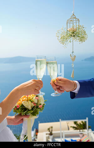 Couple de mariés avec des verres de champagne dans les mains contre la mer Banque D'Images