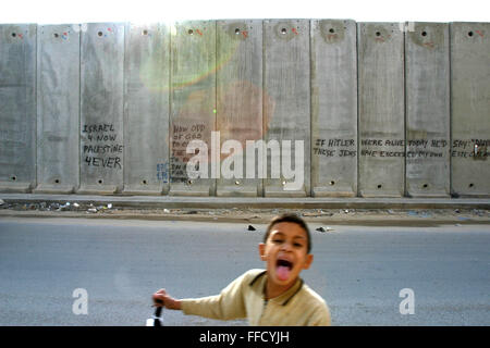 Un jeune garçon palestinien devant le mur. Des déclarations politiques sont communs decoration le long du mur construit par les Israéliens pour séparer la Palestine et Israël. Banque D'Images