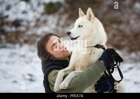 Man embracing avec Husky en forêt d'hiver Banque D'Images