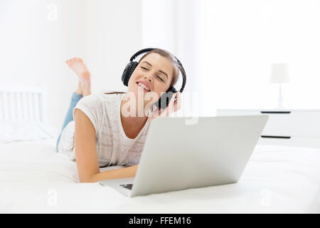 Smiling teen girl lying on bed profiter de la musique Banque D'Images