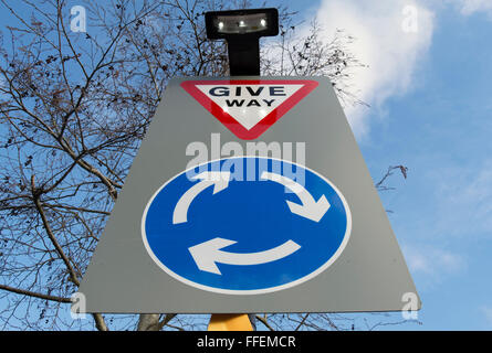 La signalisation routière indiquant un rond-point de l'avant et de donner des instructions aux usagers de la route à céder sur l'atteindre Banque D'Images