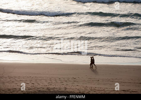 Un couple sur la plage de Baie de Holywell, North Cornwall, dans la lumière du soir Banque D'Images