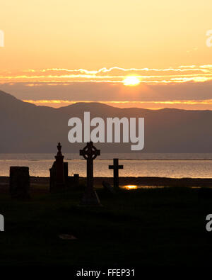 Broadford, Isle of Skye, Highland, en Écosse. Cimetière donnant sur la baie de Broadford, coucher de soleil, croix celtique d'importance. Banque D'Images