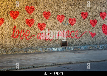 Graffito dans un passage inférieur montrant coeurs rouges et le texte : l'amour et de la paix Banque D'Images