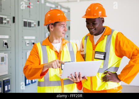 Les techniciens professionnels masculins à l'aide d'ordinateur portable dans la salle de commande Banque D'Images