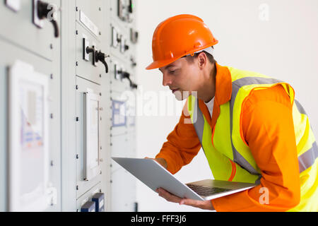 Ingénieur industriel de sexe masculin à l'aide d'ordinateur portable dans la salle de commande Banque D'Images