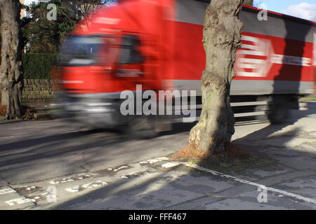 Un camion conduit par un arbre qui grandit au milieu d'un carrefour sur une route bordée d'arbres dans une banlieue de Sheffield, Yorkshire UK Banque D'Images