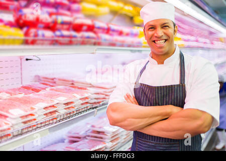 Cheerful senior butcher debout dans une boucherie Banque D'Images