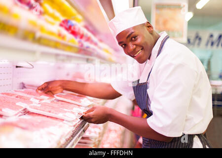 Happy African butcher travaillant dans une boucherie Banque D'Images