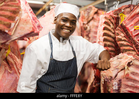 Certains hommes africains butcher debout près de viande suspendues Banque D'Images