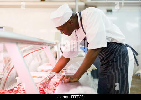 Young African American butcher ramasser des morceaux de viande dans une boucherie Banque D'Images