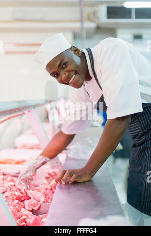 Happy African American butcher picking raw meat Banque D'Images