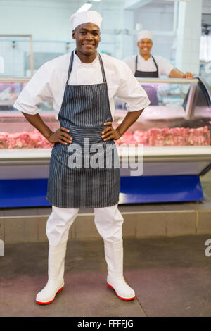 Heureux de l'Afrique de l'homme posant en boucherie charcuterie Banque D'Images