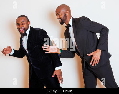 Deux hommes d'afro-américaine en costumes noirs qui posent des gestes, émotionnelle, souriant. Le port de liens à l'arc Banque D'Images