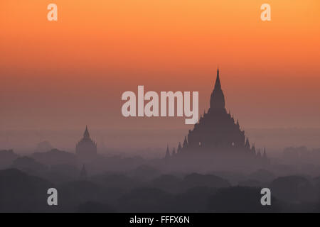 Misty incroyable lever du soleil couleurs et silhouette de l'ancienne Pagode Myauk Guni. L'architecture des temples bouddhistes antiques à Bagan King Banque D'Images