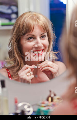 Young woman putting on necklace salle de bains Banque D'Images